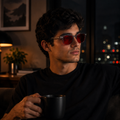 Homem usando óculos AURA Night Smoke com armação cinza translúcida e lentes vermelhas em ambiente noturno.
