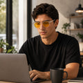 Homem usando óculos NOX Day Translucent com lentes amarelas e filtro de luz azul enquanto trabalha no notebook.