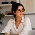 Mulher usando óculos LUMA Day com armação Tortoise e lentes amarelas em um ambiente interno moderno e aconchegante, com foco no rosto e no formato ovalado dos óculos.